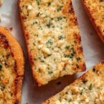 Golden brown slices of air fryer garlic bread topped with melted butter and parmesan cheese.