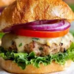 Four golden brown turkey burgers with melted cheese on toasted buns