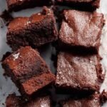 A stack of fudgy chocolate brownies made with oat flour on a cooling rack.