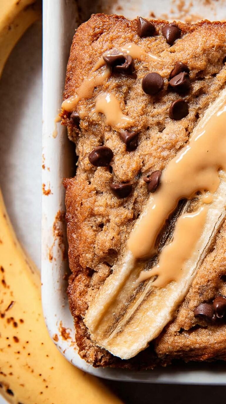 A warm mug containing a single serving of banana bread topped with a small pat of melting butter.