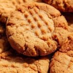 Golden brown peanut butter cookies with fork marks in an air fryer basket