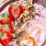 A thick strawberry smoothie bowl topped with granola, chia seeds, and fresh berries.