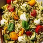 A bright bowl of Orzo Pesto Salad with cherry tomatoes and mozzarella pearls