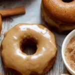 A plate of golden brown baked banana donuts coated in sparkly cinnamon sugar.