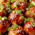 Glazed Asian chicken meatballs in a bowl with sesame seeds and scallions