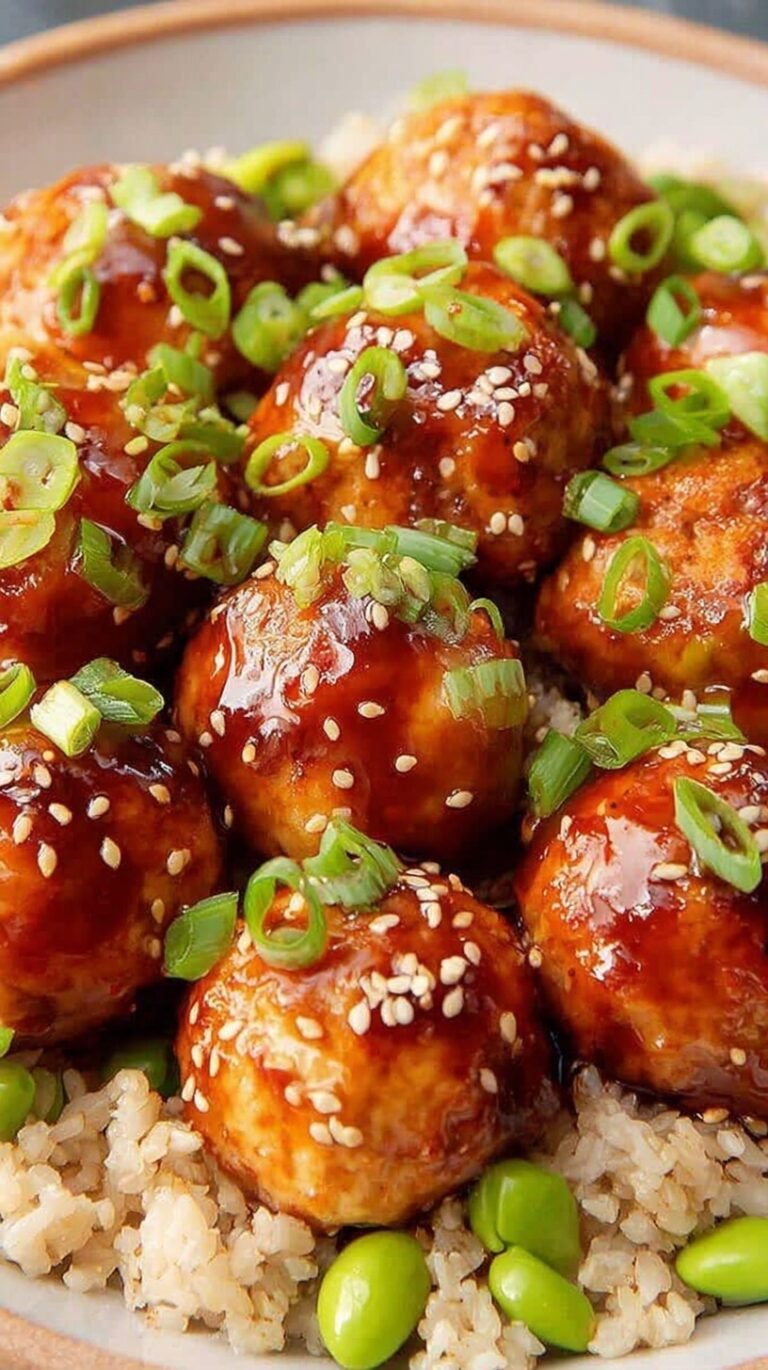 Glazed Asian chicken meatballs in a bowl with sesame seeds and scallions