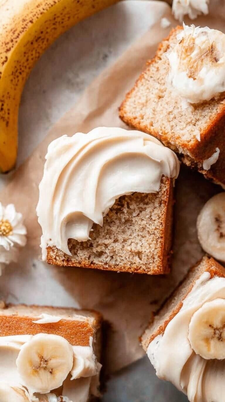 A square gluten-free banana cake on a wire rack being sliced for serving.