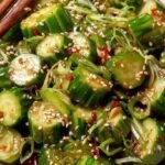 A chilled bowl of smashed spicy cucumber salad with chili oil, garlic, and fresh cilantro.