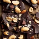 Pieces of dark chocolate peanut bark with sea salt on parchment paper