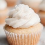 A tray of golden healthy vanilla cupcakes sitting on a wire cooling rack.