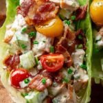 A bowl of creamy chicken salad with bacon, tomatoes, and romaine lettuce.