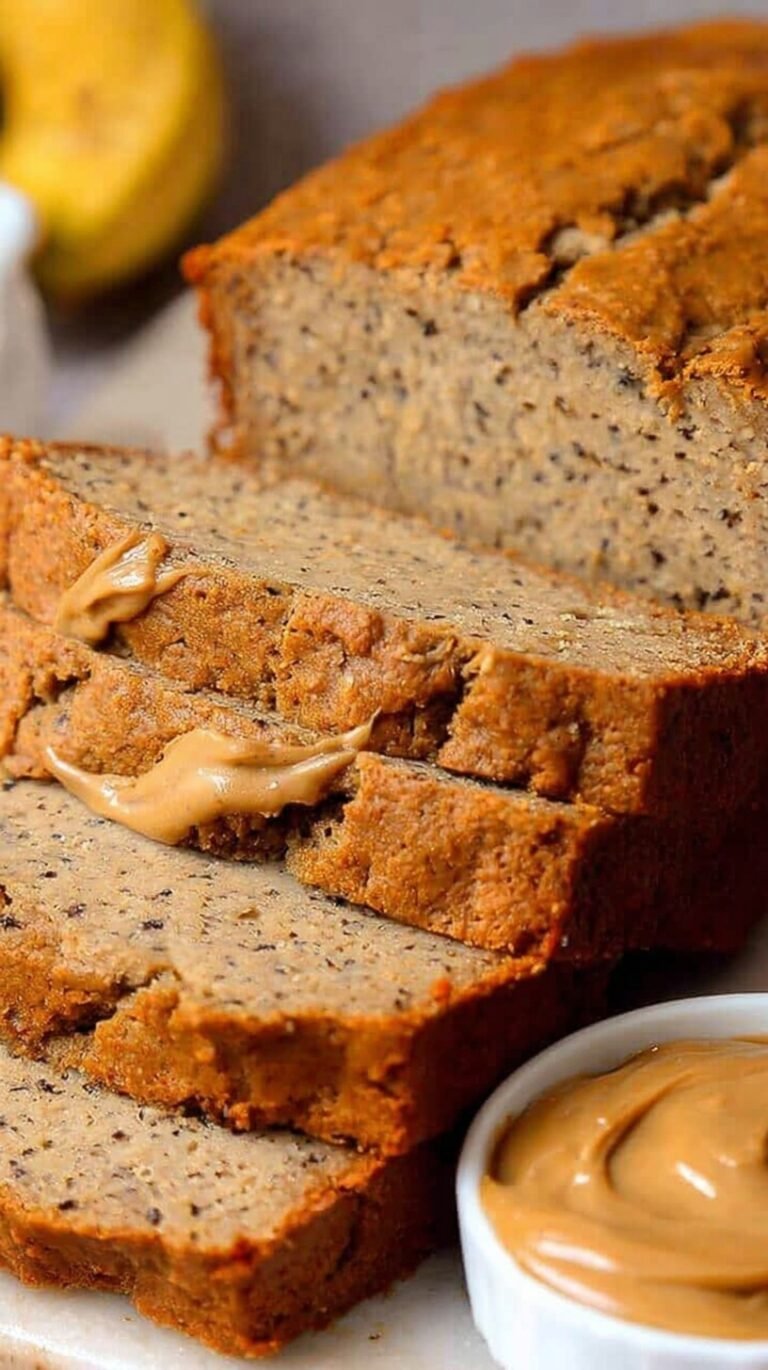 A sliced loaf of healthy peanut butter banana bread on a wire cooling rack.