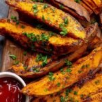 A basket of golden brown, crispy air fryer sweet potato wedges seasoned with smoked paprika and sea salt.