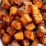 Golden brown seasoned sweet potato cubes in an air fryer basket
