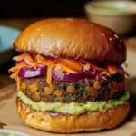 A hearty roasted black bean burger on a toasted bun with avocado and sprouts