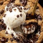 A warm chocolate chip cookie skillet with melted chocolate chips and golden edges in a cast iron pan.