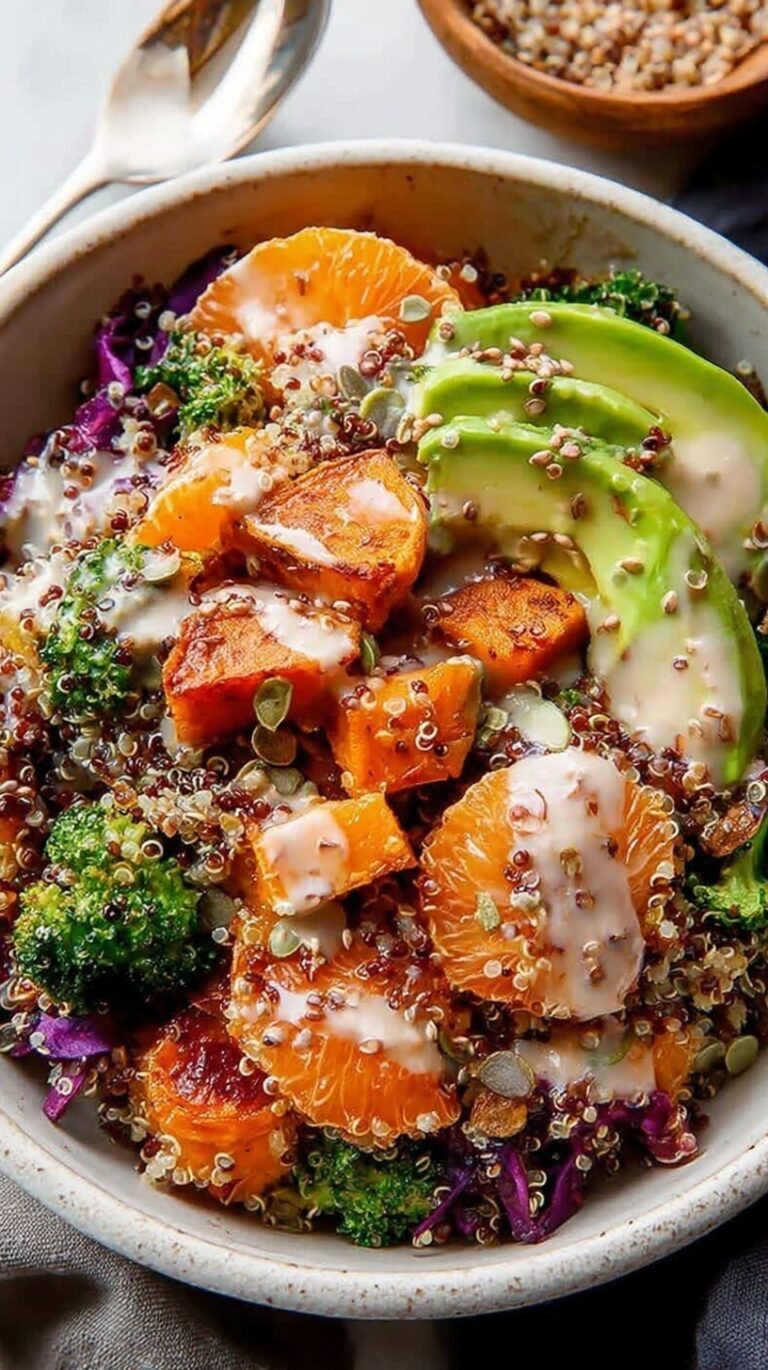 A colorful quinoa sweet potato bowl with black beans, kale, and avocado drizzled with tahini dressing.