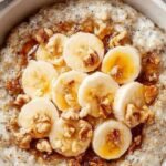 A cozy white bowl filled with fluffy oatmeal topped with cinnamon and honey