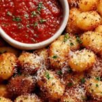 Golden brown crispy air fryer gnocchi tossed with parmesan cheese in a bowl