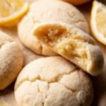 A plate of soft vegan lemon sugar cookies with a bright white glaze and lemon zest.