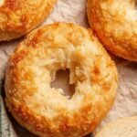 Freshly baked homemade asiago bagels with melted cheese on a wire rack