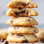 A stack of golden, crispy chocolate chip cookies made with white sugar on a cooling rack.