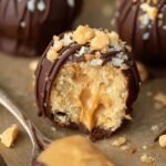 A plate of dark chocolate covered peanut butter truffles topped with sea salt