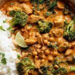 A bowl of creamy chicken peanut butter curry topped with cilantro and peanuts over jasmine rice