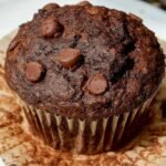 A stack of moist chocolate banana muffins with melted dark chocolate chips on top.