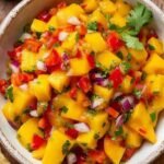 A bowl of vibrant mango habanero salsa with red onion and cilantro