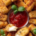 A plate of golden brown Air Fryer Mozzarella Sticks with a side of marinara sauce