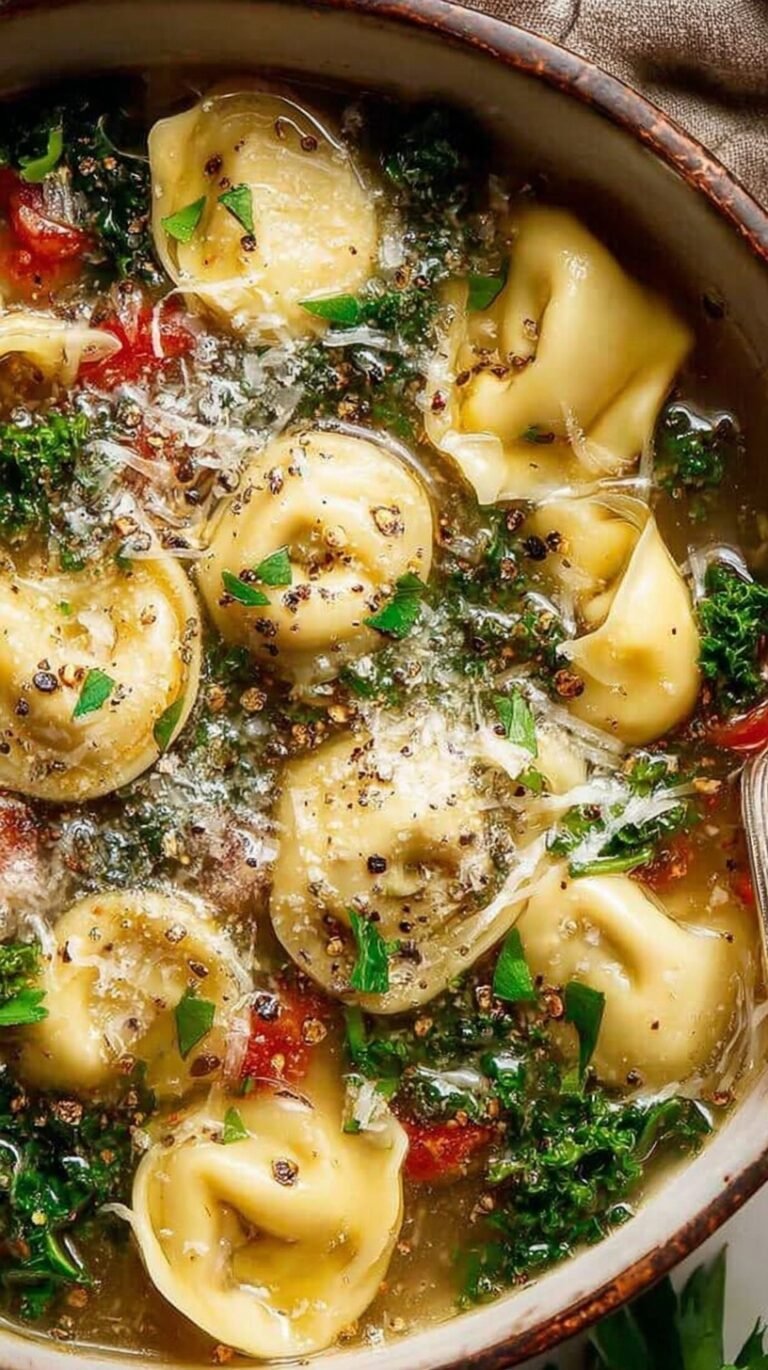 A steaming bowl of parmesan kale tortellini soup with fresh greens and cheesy pasta