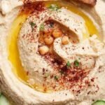 A bowl of smooth homemade blender hummus topped with olive oil and chickpeas