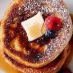Golden brown French Toast Bagels topped with maple syrup on a white plate