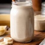 A creamy cinnamon smoothie in a glass with a dusting of cinnamon on top.