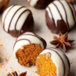 A plate of white chocolate covered pumpkin spice truffles with orange spice sprinkles.