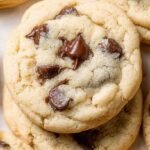 A stack of pale, soft sugar cookies filled with chocolate chips and coated in sparkling sugar.
