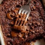 A single-serve ramekin of chocolate baked oats topped with melted chocolate chips.