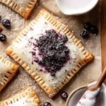 Golden brown blueberry pop tarts with purple glaze on a wire cooling rack