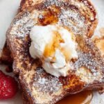 Golden brown slices of high protein french toast topped with cinnamon on a white plate.