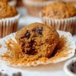 A stack of golden brown pumpkin muffins made with oat flour on a cooling rack.