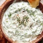 A bowl of creamy healthy low-fat tzatziki topped with fresh dill and cucumber slices