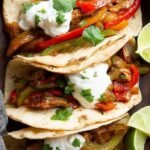 A platter of colorful chicken fajita tacos with lime wedges and cilantro