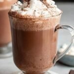 A steaming mug of creamy oat milk hot chocolate topped with chopped dark chocolate.