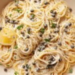A bowl of creamy lemon caper pasta with fresh parsley and parmesan cheese