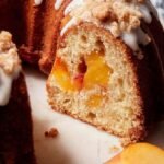 A golden brown Peach Cobbler Pound Cake with a crumble topping on a wire rack
