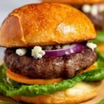 A juicy bison burger with melted cheddar cheese on a toasted brioche bun with lettuce and tomato