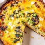 A golden gluten-free feta quiche with spinach in an almond flour crust on a table.