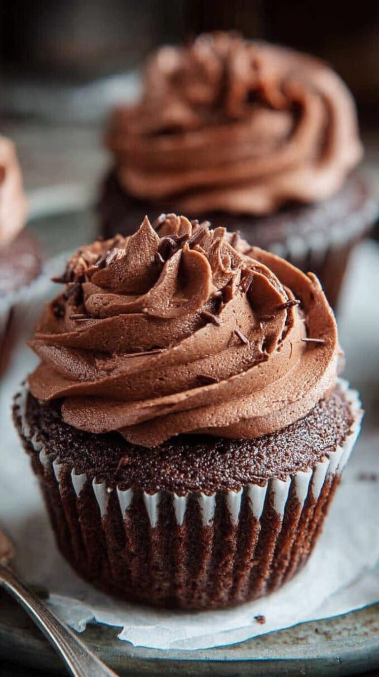 A tray of twelve moist gluten-free chocolate cupcakes with a deep cocoa color and tender crumb.