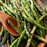 Crispy air fried green beans in a basket with garlic parmesan topping